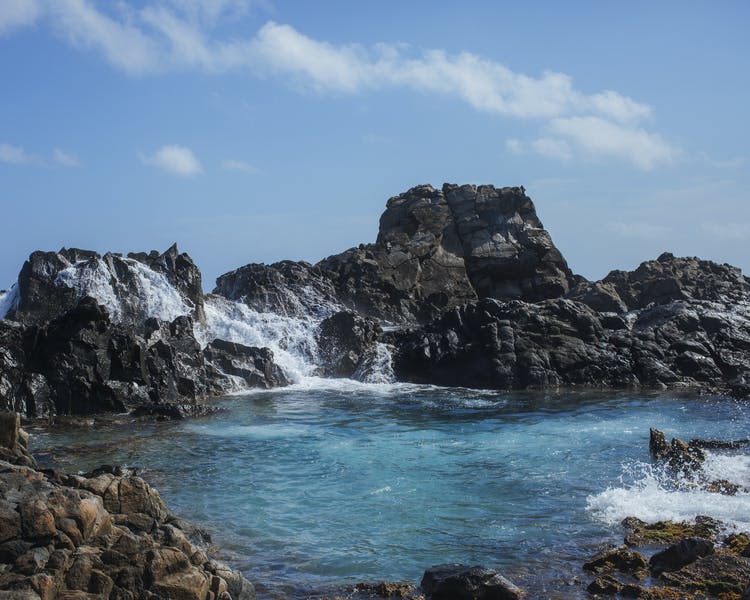 Rock formation with water crashing against it.